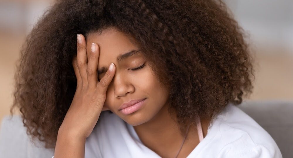 A young woman has her hand on her face.