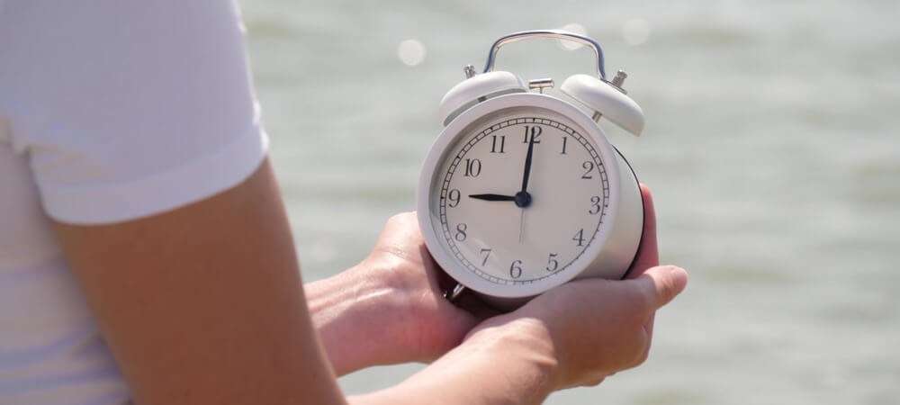 A women holding a clock watching the time. 