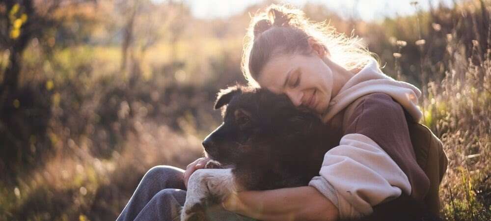 Women smiling while hugging her dog. 