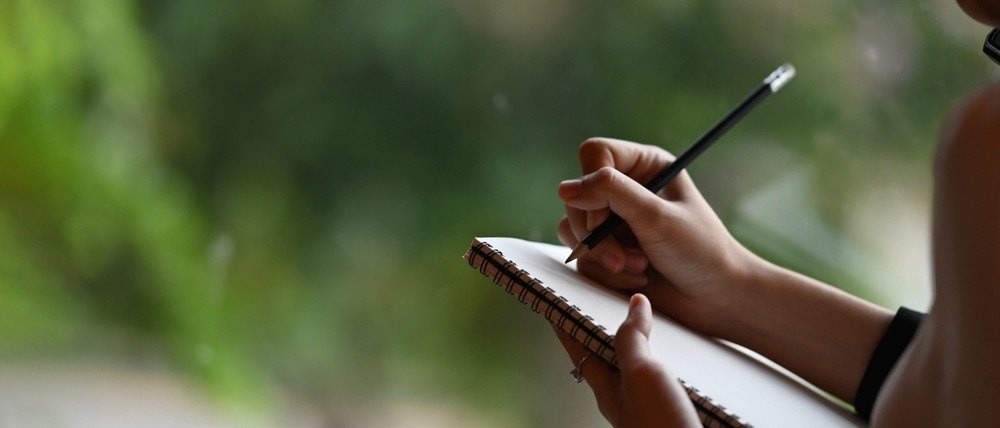A woman writing down notes in her notepad.