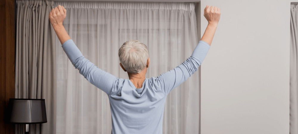 Elderly woman stretches after a good nights sleep. 