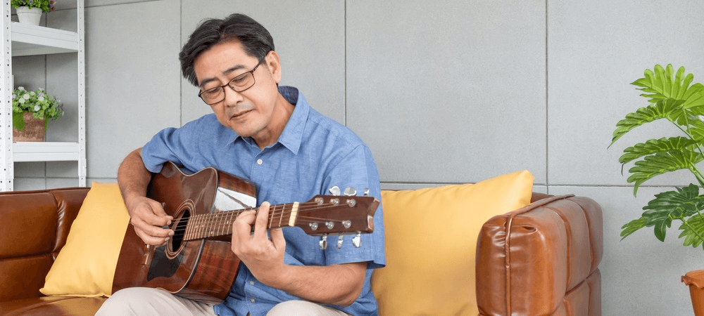 Elderly man plays guitar. 