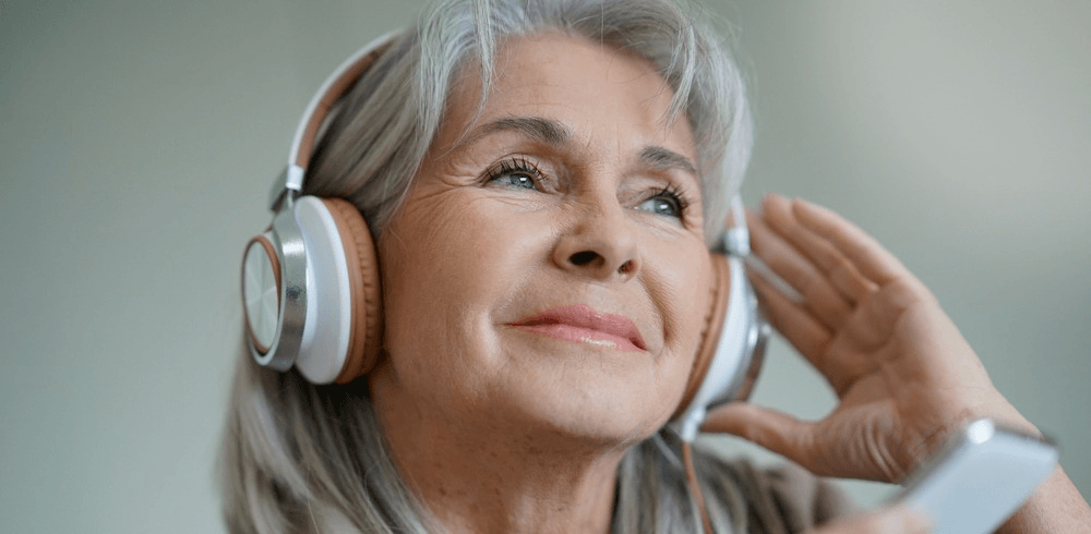 Elderly woman listens to music. 