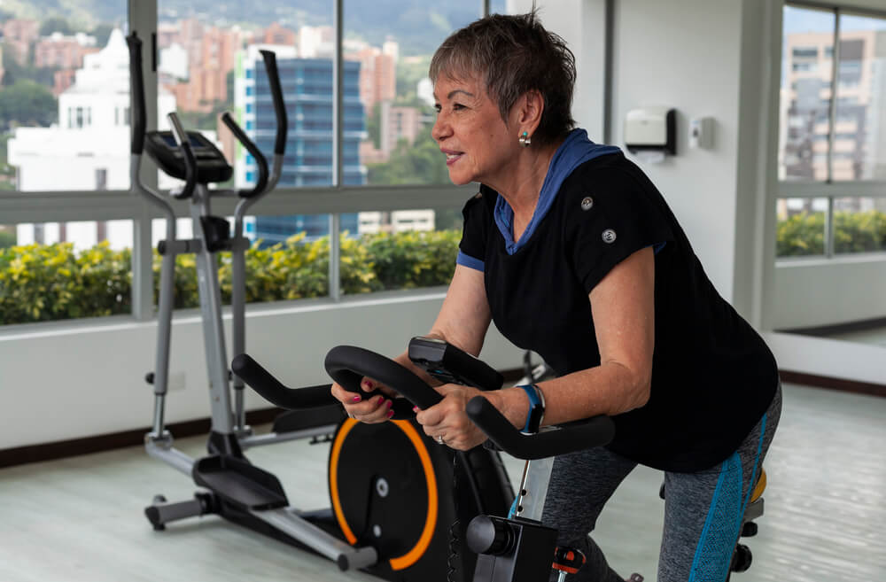 A woman is working out on a stationary bicycle