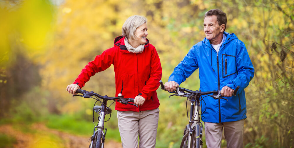 Active seniors walking their bicycles