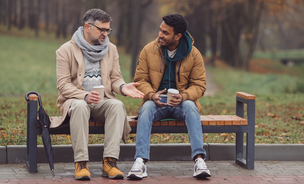 Two friends chatting on a bench at the park