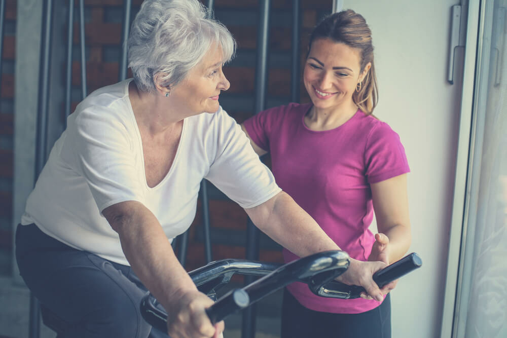 Senior woman exercises on a stationary bike. 