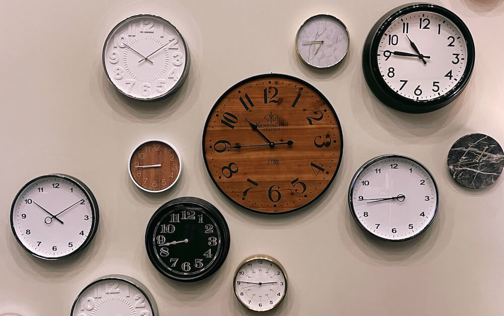 several clocks on a wall with different times on each clock
